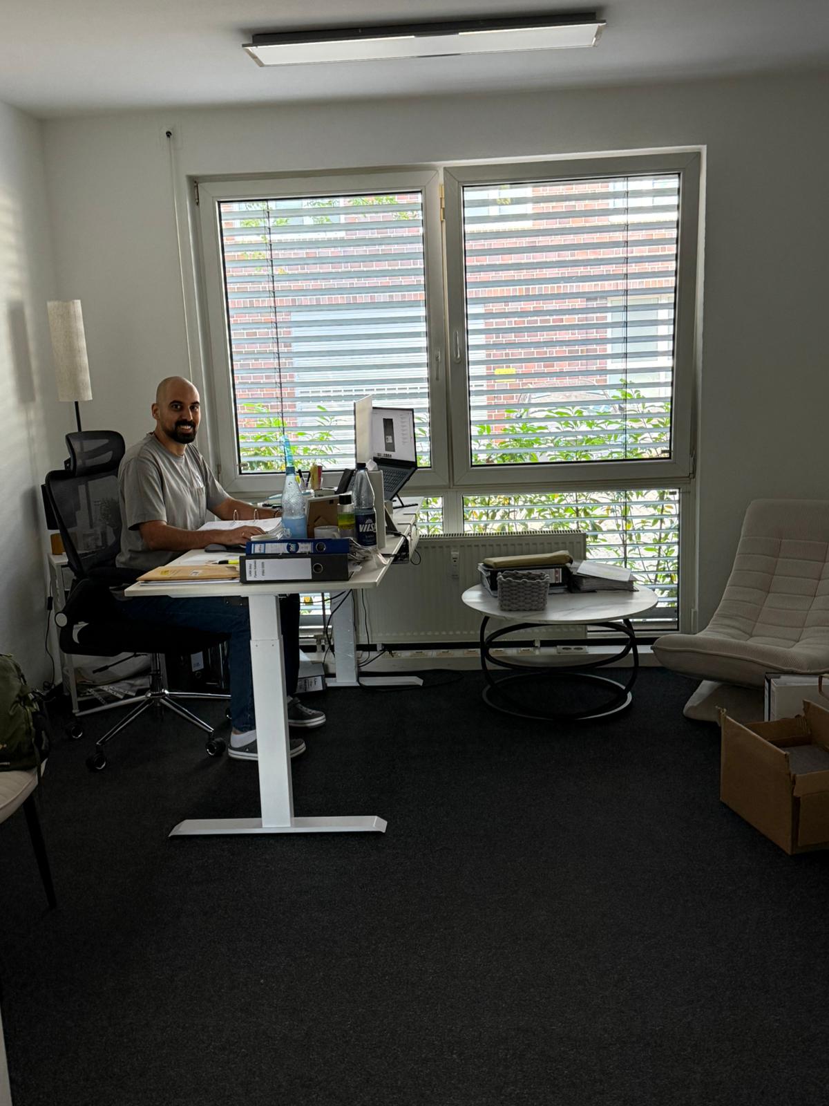 Mitarbeiter am Arbeitsplatz mit Ordnern und Bildschirm