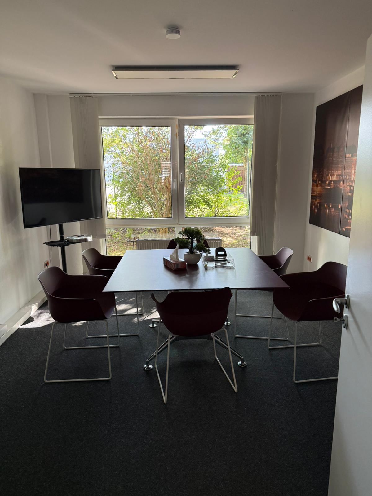 Besprechungsraum mit großem Tisch, Bildschirm und Bremen-Motiv an der Wand
